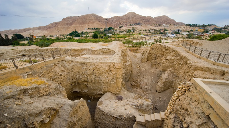 Arkeologisk utgrvning i Jeriko, med en liten by och en bergstopp i Juda ken i bakgrunden.